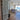 Modern double hinged glass door with metal frame opening to living room with sofa and ocean view