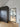 Modern interior with black framed glass hinged door and dark textured wardrobe on wooden floor