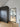 Modern interior with black framed glass hinged door and dark textured wardrobe on wooden floor
