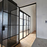 Modern interior with black-framed glass hinged door and light wood flooring
