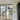 double hinged black metal framed glass doors partitioning a bright room with wooden stairs and light wood flooring