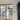 double hinged black metal framed glass doors partitioning a bright room with wooden stairs and light wood flooring
