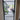 Modern black-framed glass hinged door with view into bright living space and indoor plants