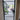 Modern black-framed glass hinged door with view into bright living space and indoor plants