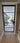 Modern black-framed glass hinged door with view into bright living space and indoor plants