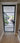 Modern black-framed glass hinged door with view into bright living space and indoor plants