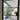 Black metal framed glass hinged door showing modern indoor patio with large plant and purple sofa