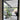 Black metal framed glass hinged door showing modern indoor patio with large plant and purple sofa