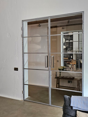 Modern double hinged glass door with metal frame in a minimalist interior space