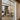 Double hinged glass door with metal frame revealing a dining room with wooden chairs and pendant lights