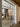 Double hinged glass door with metal frame revealing a dining room with wooden chairs and pendant lights