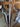 Close-up of modern stainless steel double hinged door handles on glass doors with wooden chairs in background