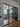 Modern living room with black-framed glass double doors, blue walls, wooden floor, and cozy seating