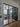 Interior view through black steel double door with side panels into modern living room with wooden floor