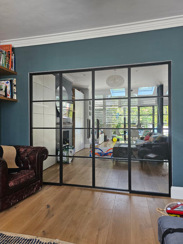 Modern black framed double glass door with two side panels in living room with blue wall and wooden floor