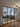 Modern living room with glass double doors featuring black frames, gray sectional sofa, patterned rug