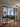 Modern living room with glass double doors, gray sectional sofa, geometric rug, and decorative ceiling light