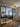 Modern living room with gray sectional sofa, patterned rug, black metal framed glass double doors
