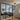 Modern living room with black framed glass double doors, gray sectional sofa, patterned rug, and stylish ceiling light