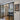 Modern black-framed glass double door with side panels leading to a hallway with wooden floor and decorative wall art