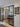 Modern black-framed glass double door with side panels leading to a hallway with wooden floor and decorative wall art