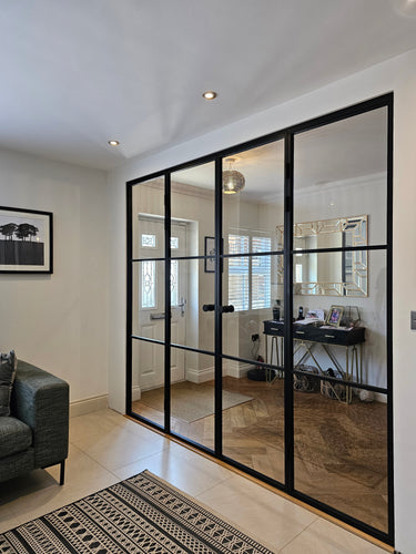 Modern black frame double glass doors with side panels separating living room and entryway