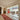 Interior hallway with wooden floor, red patterned runner rug, large glass double doors, and a sunlit dining area with red cabinet