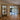 Modern interior featuring black-framed glass double doors with side panels separating living and kitchen areas