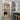 Modern kitchen with blue island, wooden stools, bookshelf, and double hinged glass doors leading to hallway