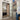 Double hinged glass door with black frame in modern kitchen with built-in bookshelves and tiled floor