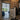Interior view of black metal-framed glass double hinged door leading to bright kitchen with blue cabinets and garden