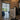 Interior view of black metal-framed glass double hinged door leading to bright kitchen with blue cabinets and garden