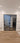 Modern double hinged glass door with black metal frame in interior with wood-look tile flooring