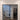 Double hinged black metal frame glass door with white walls and wood-style tiled floor