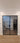 Double hinged black metal frame glass door with white walls and wood-style tiled floor
