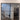 Double hinged black metal frame glass door in modern home entryway with wood tile floor