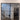 Double hinged black metal frame glass door in modern home entryway with wood tile floor