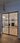 Modern double hinged black metal frame door with glass panels opening to stylish living room