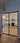 Modern double hinged black metal frame door with glass panels opening to stylish living room