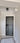 Modern black hinged interior door with frame in white hallway with marble patterned floor and geometric light fixture