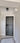 Modern black hinged interior door with frame in white hallway with marble patterned floor and geometric light fixture