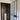 modern frosted glass hinged door with black frame leading to bathroom with round pedestal sink and dark tiled walls