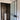 modern frosted glass hinged door with black frame leading to bathroom with round pedestal sink and dark tiled walls