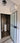 modern frosted glass hinged door with black frame leading to bathroom with round pedestal sink and dark tiled walls