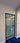 Modern black framed glass hinged door with white trim and blue carpeted floor