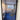 Black framed glass hinged door with handle reflecting a modern living room with blue carpet and furniture