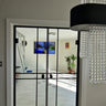 Modern interior with black double hinged glass doors, white walls, tiled floor, and chandelier