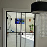 Modern interior with black double hinged glass doors, white walls, tiled floor, and chandelier