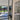 Modern double hinged glass door with black frame opening to bright tiled room and garden view