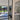 Modern double hinged glass door with black frame opening to bright tiled room and garden view